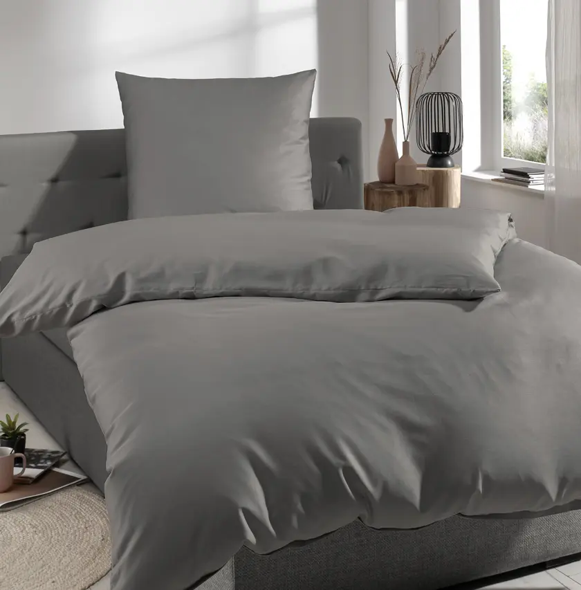 Modernes Bett mit grauer Bettwäsche und großem Kopfkissen in stilvollem Schlafzimmer – ideal für Schlafkomfort, hochwertige Bettwaren und zeitlose Wohnideen für Schlafzimmergestaltung.